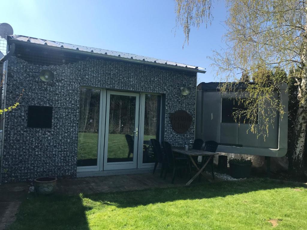ein Haus mit einer Terrasse und einem Tisch im Hof in der Unterkunft Dailly Chalet in Couvin