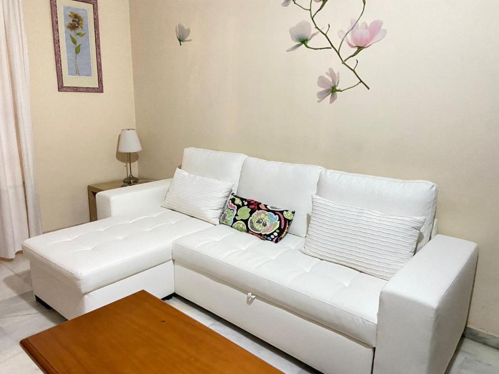マラガにあるApartamento CENTRICO Mare Nostrumの白いソファ付きのリビングルーム(花の壁付)