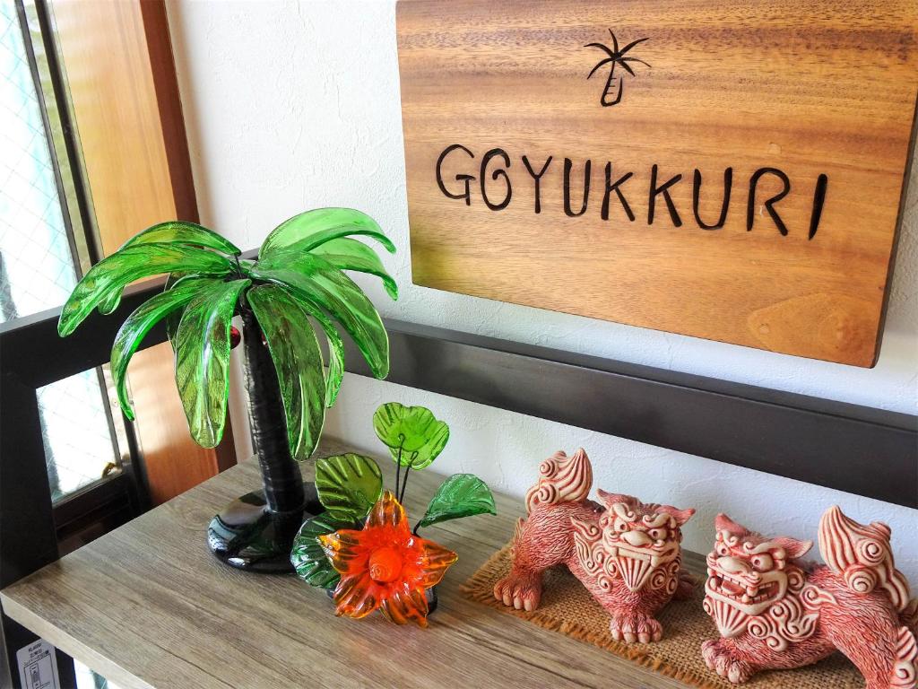 Minshuku Itoman Bettei Goyukkuri في إيتومان: طاولة عليها نبات وبعض التماثيل