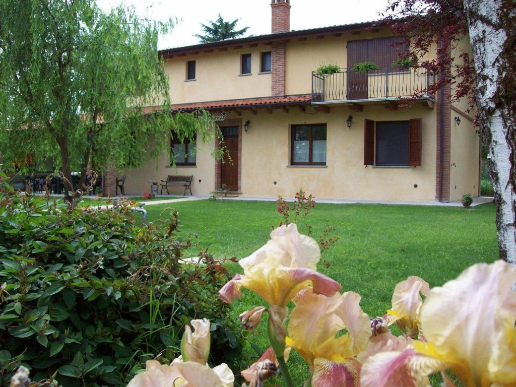 a house in the back of a yard with flowers at Agri Village Pavia in Certosa di Pavia