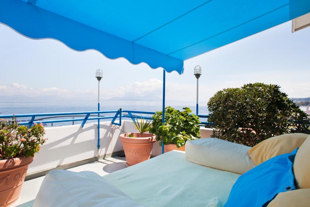 a balcony with a blue umbrella and some plants at Daphne's Club Hotel Apartments in Xylokastro