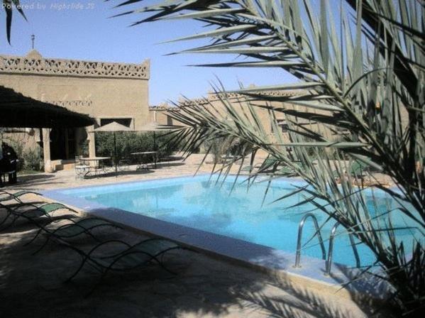 a large swimming pool with chairs and a building at Les Portes Du Desert in Merzouga