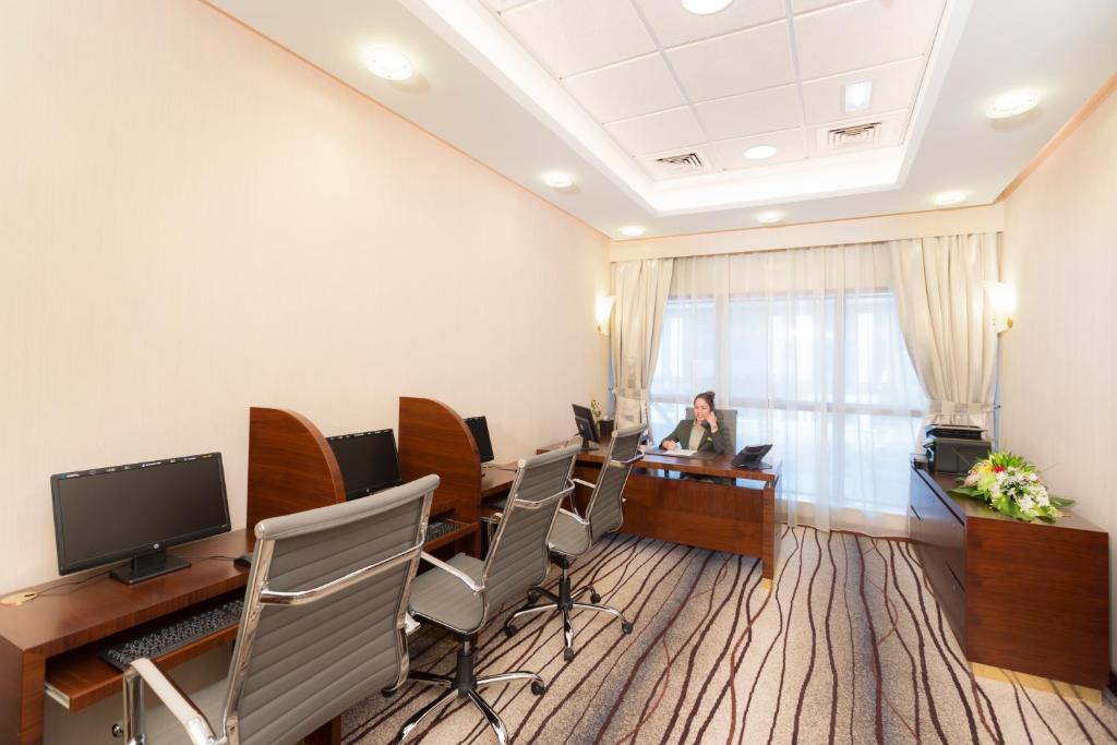 a woman sitting at a desk in a conference room at Grand Mercure Majlis Residences in Abu Dhabi