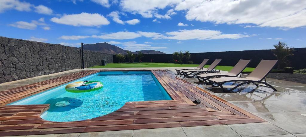 een zwembad met ligstoelen en een vlot in het water bij Villa Geneva - Relax y diversión in Playa Blanca