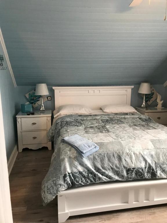 a bedroom with a bed and two night stands with lamps at gite des iles in Matane