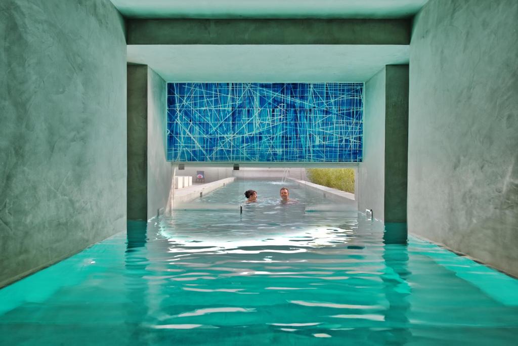 a swimming pool with two people in the water at Hotel Wu Wei in Kortrijk