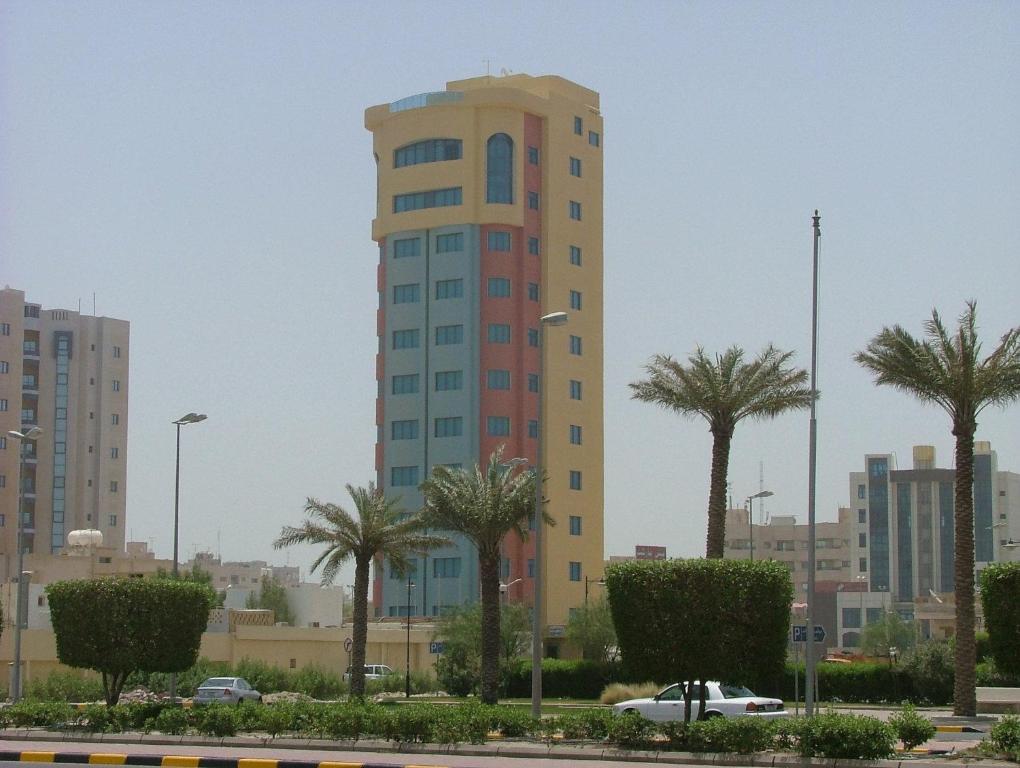 a tall building with palm trees in a city at Le Royal Corniche in Kuwait