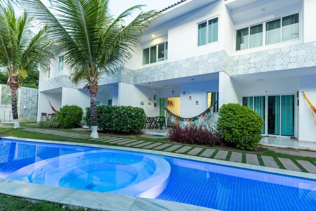 a villa with a swimming pool in front of a house at Excelente casa para temporada em porto de galinhas casa 8 in Porto De Galinhas