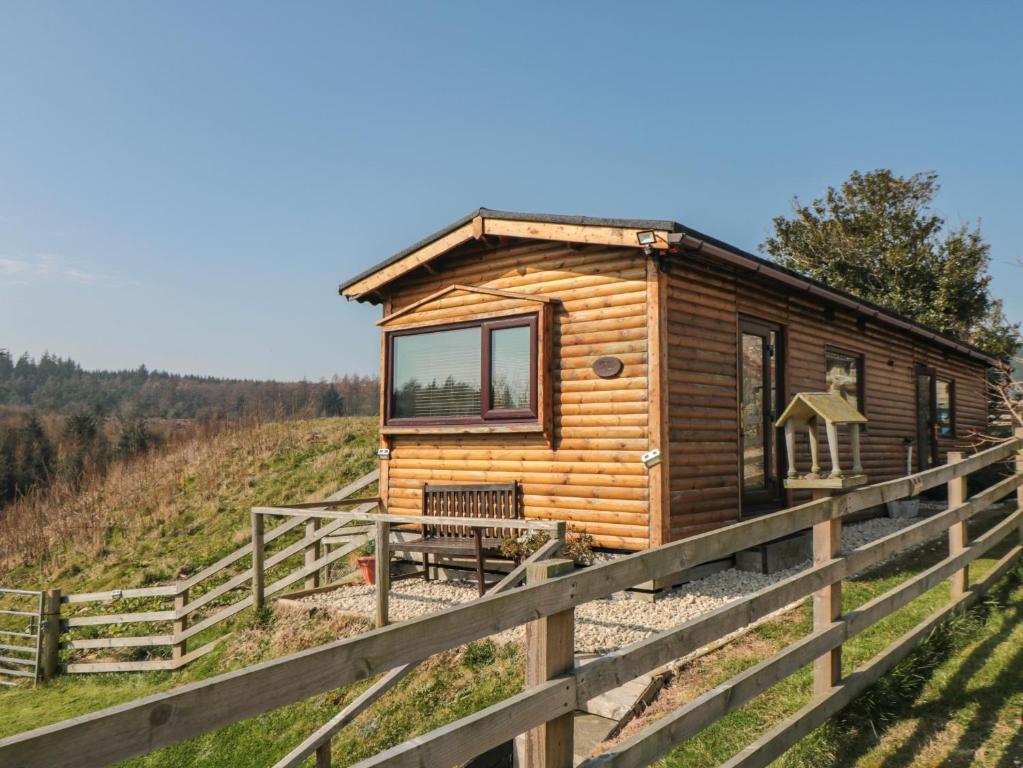 eine Holzhütte auf einem Hügel mit einem Zaun in der Unterkunft Castle View Cabin in Scarborough