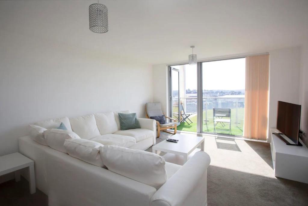 a living room with a white couch and a large window at Stunning 2 Bedroom Apartment in Ashley Down with Cricket View in Bristol