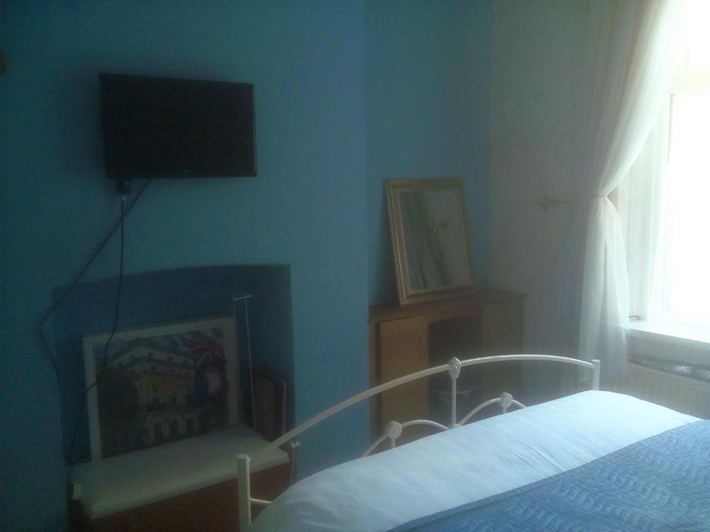 a bedroom with a bed and a flat screen tv at Welsh Homestay in Cardiff