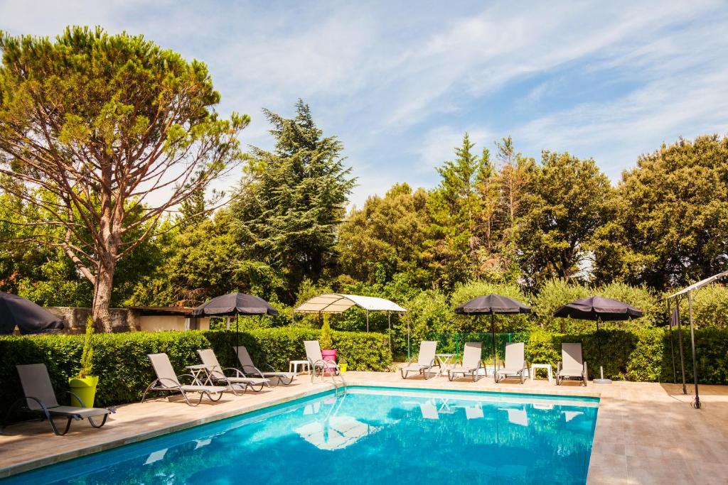 - une piscine avec des chaises longues et des parasols dans l'établissement Le Petit Manoir Logis, aux Angles (Gard)