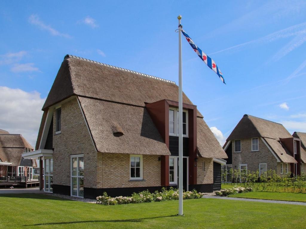 una casa con un palo di bandiera davanti di Luxury villa with a sauna, at the Tjeukemeer a Delfstrahuizen