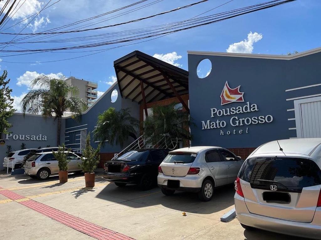 un estacionamiento con autos estacionados frente a un edificio en Hotel Pousada Mato Grosso en Campo Grande