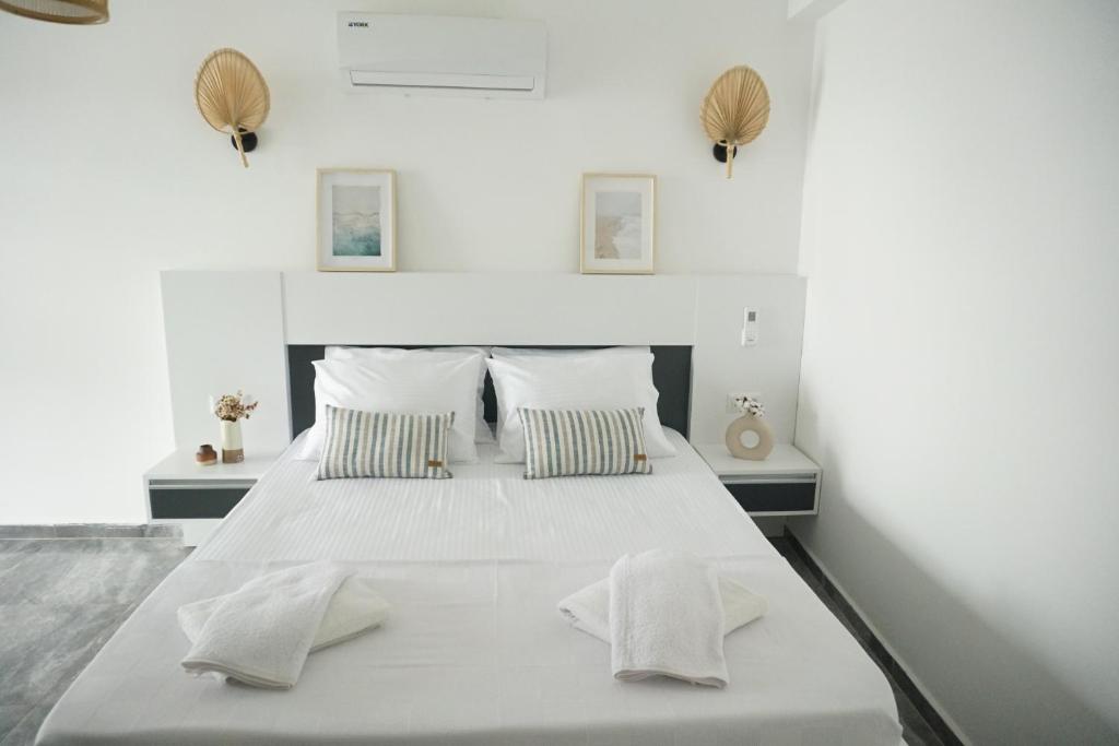 a white bedroom with a large white bed with two pillows at Blue Island Luxury Hotel Adults Only in Kaş