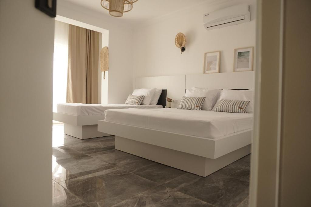 two beds in a bedroom with white walls and tile floors at Blue Island Luxury Hotel Adults Only in Kaş