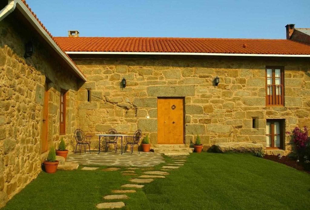 a stone house with a patio with a table and chairs at Casa Rural A Cobacha in Paderne
