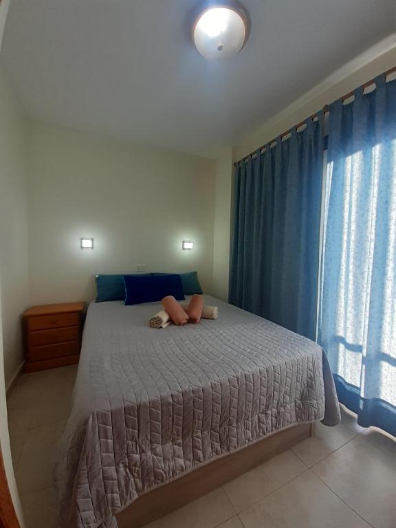 1 dormitorio con 1 cama grande y cortinas azules en Casa Yuni, en Candelaria