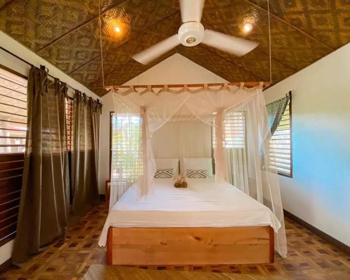 una camera con letto a baldacchino e ventilatore a soffitto di Herbs Guest House and Restaurant near the Sea a Moalboal