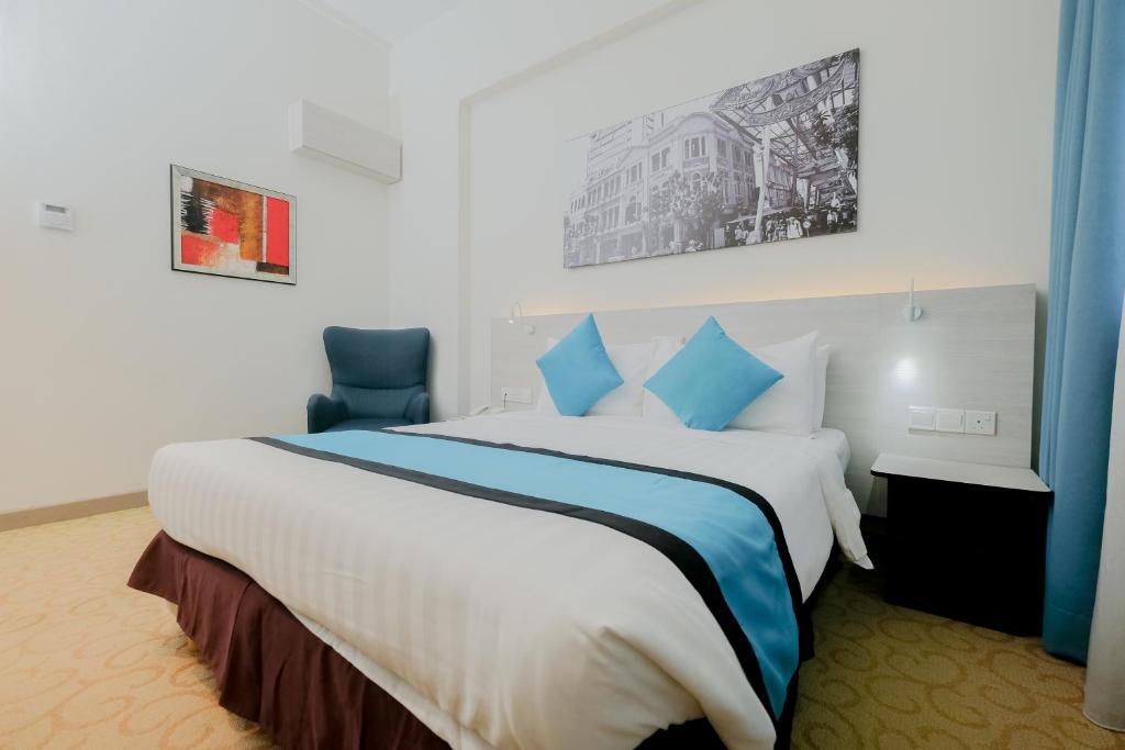 a hotel room with a large bed with blue pillows at EDC Hotel Kuala Lumpur in Kuala Lumpur
