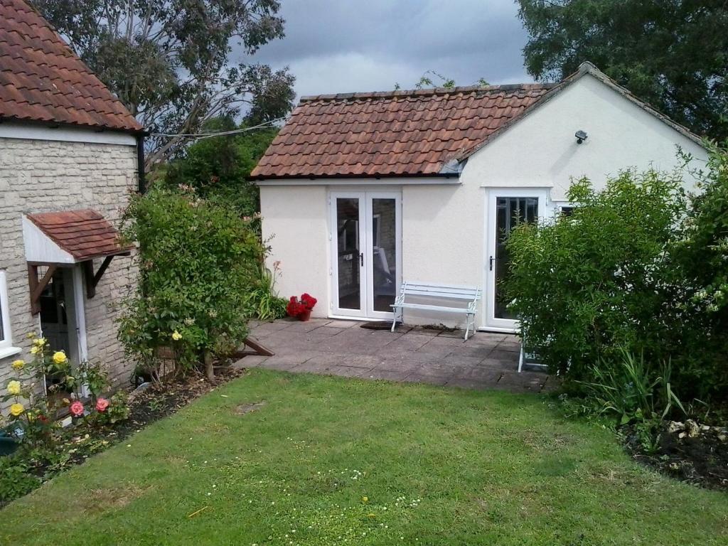 a small white house with a bench in the yard at Yew Tree View in Marnhull