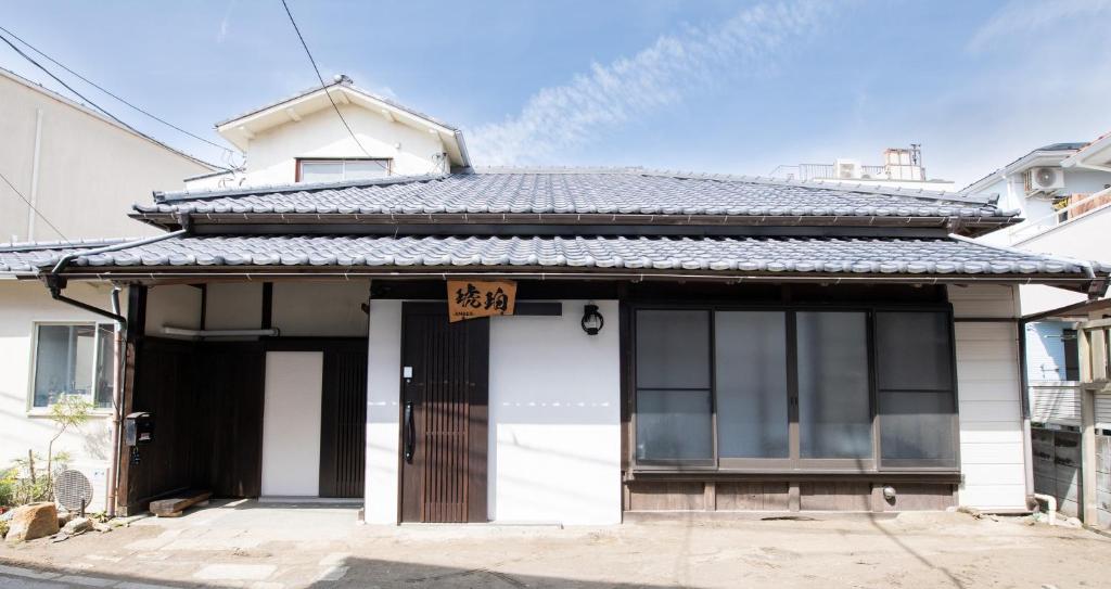 un pequeño edificio blanco con un cartel en la puerta en Kohaku AMBER Kamakura Zaimokuza en Kamakura