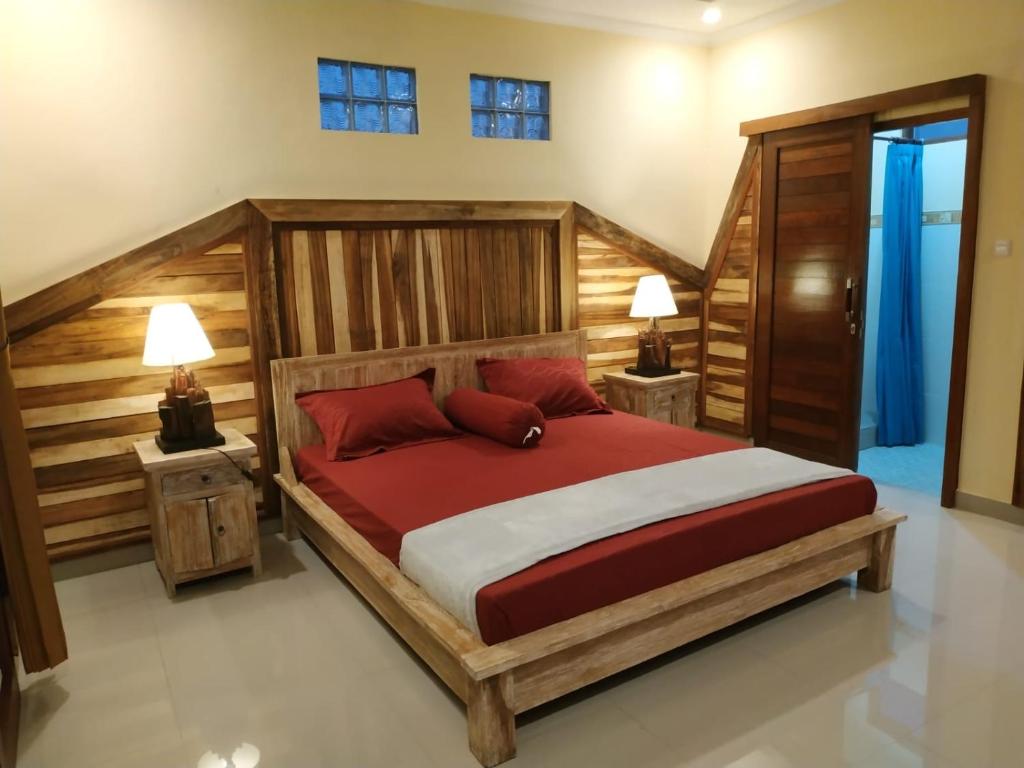 a bedroom with a large wooden bed with red pillows at Bali Soul Guest House & Apartments in Ubud