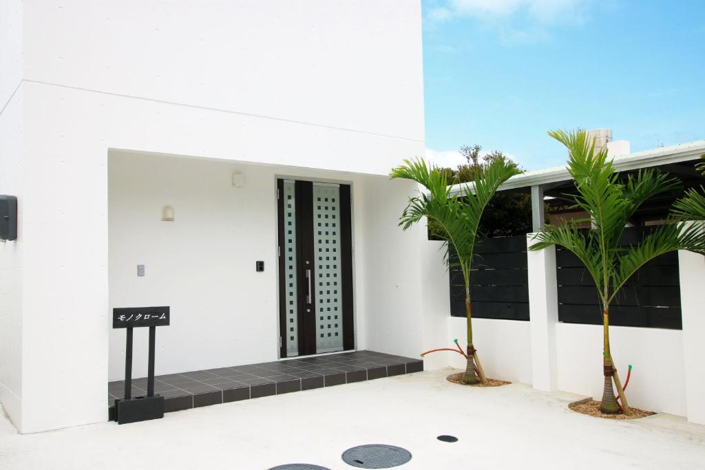 a white building with palm trees in front of it at MONOCHROME -SEVEN Hotels and Resorts- in Yomitan