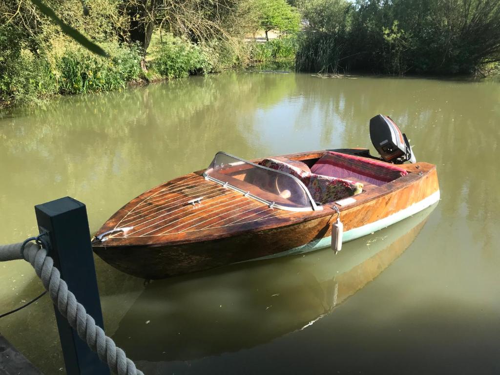 a wooden boat tied up to a dock in the water at Gorgeous Bruton Chic Lakeside Boat House. in Bruton