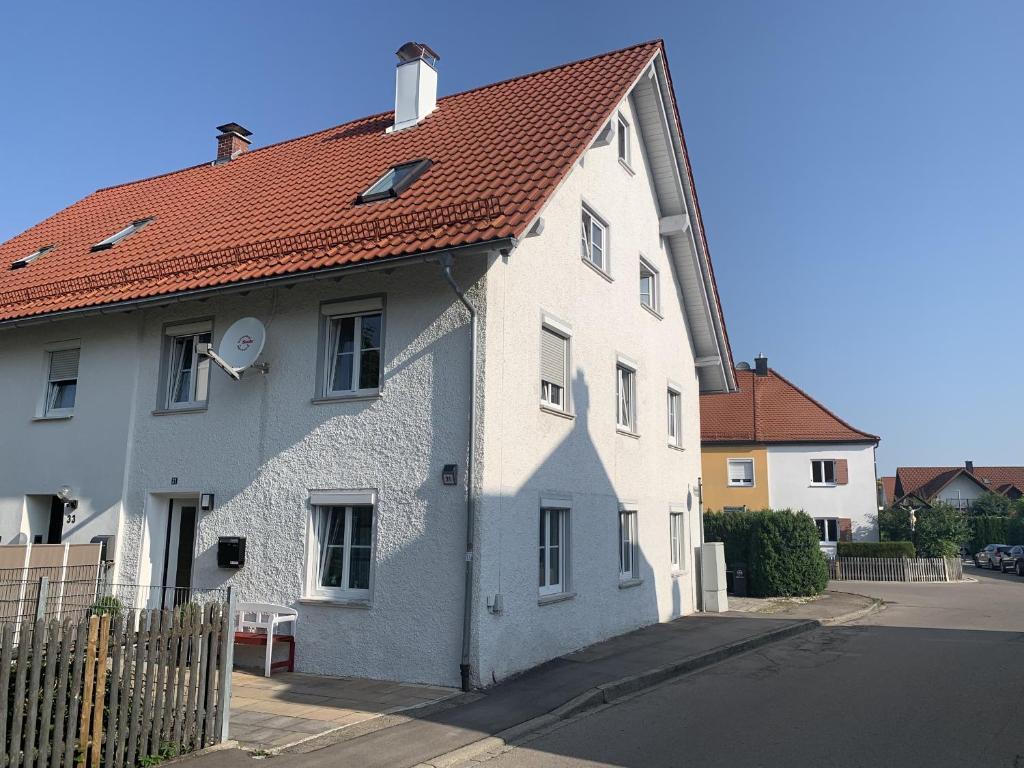 une maison blanche avec un toit rouge dans une rue dans l'établissement FeWo HoLiDay HouSE Allgäu, à Ottobeuren