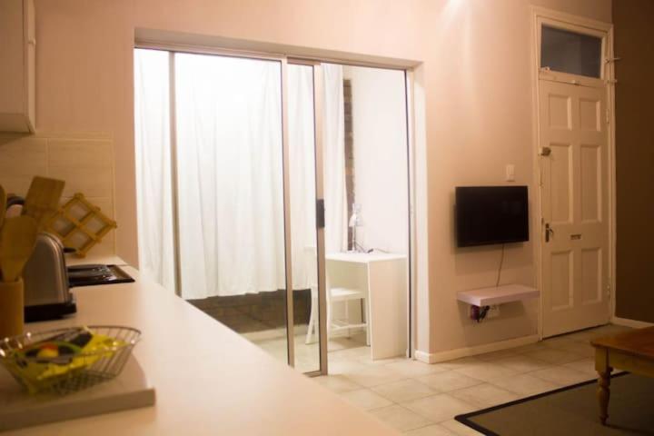 cocina con puerta corredera de cristal a la sala de estar en Limbila House, en Ciudad del Cabo
