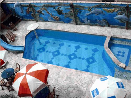 a swimming pool with two umbrellas in front of a swimming pool at Peruíbe Suíte Flat Hotel in Peruíbe