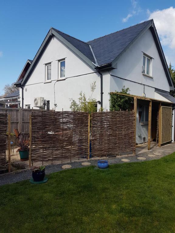 a white house with a wooden fence in a yard at Post Office Row Apartment and garden in Crickhowell