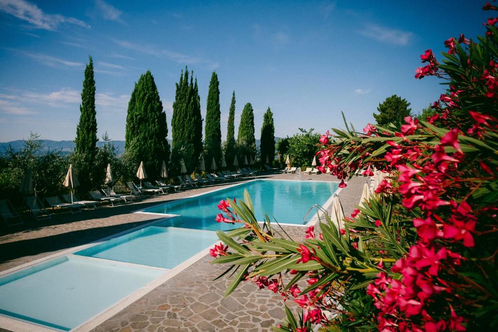 a swimming pool with some pink flowers and trees at Usignoli Apartments - Happy Rentals in Reggello