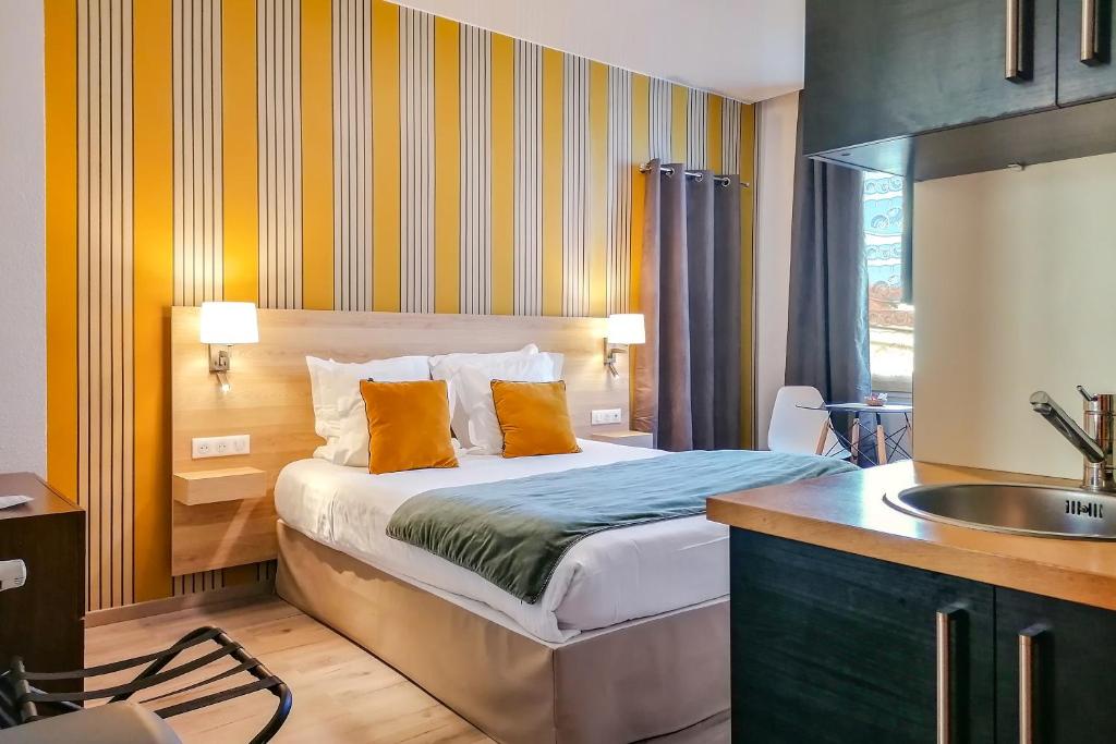 a bedroom with a bed with orange pillows and a sink at Ajoupa Aparthotel AMMI Massena in Nice
