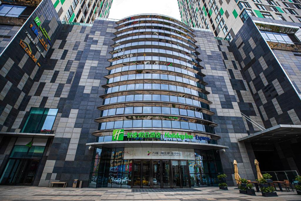 un edificio alto con un cartel en la parte delantera en Holiday Inn Express Yingkou Onelong Plaza, an IHG Hotel, en Gaizhou