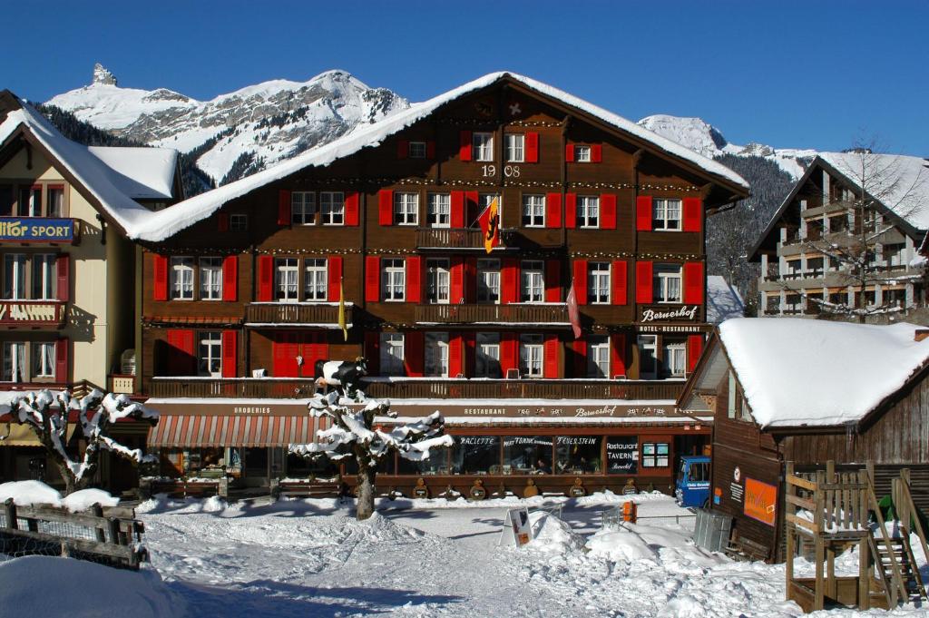 a large wooden building with snow on it at Swiss Lodge Hotel Bernerhof in Wengen