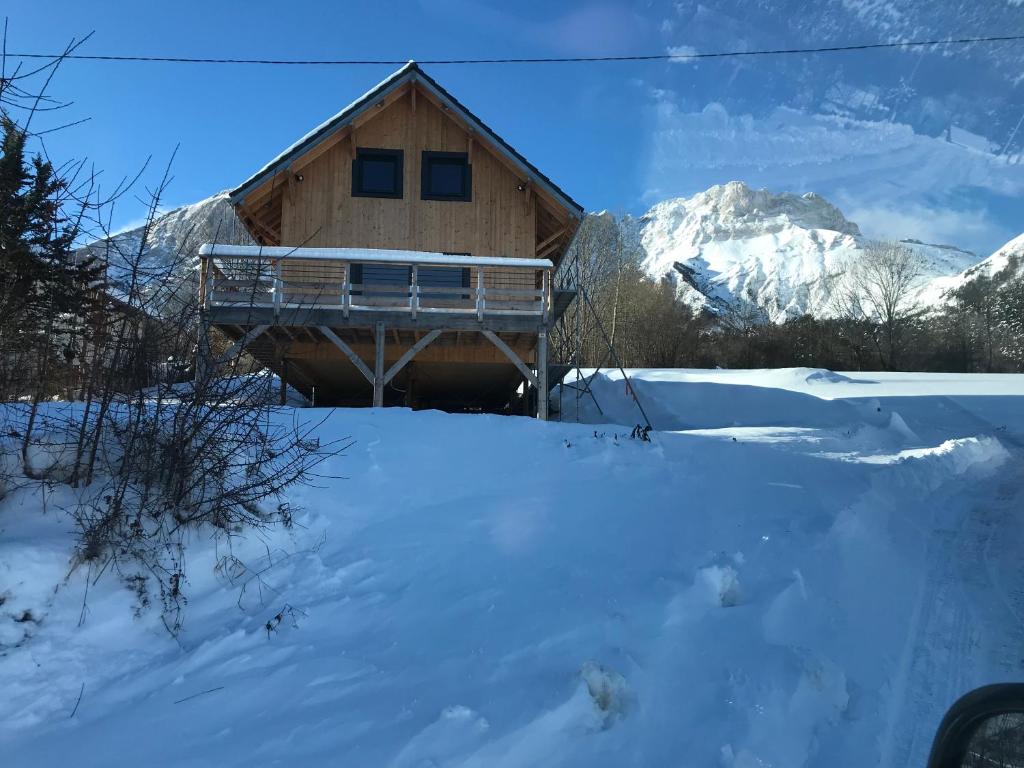 une cabane en rondins dans la neige avec des montagnes en arrière-plan dans l'établissement Chalet Gîte Magali de 2 à 12 pers, à Le Noyer