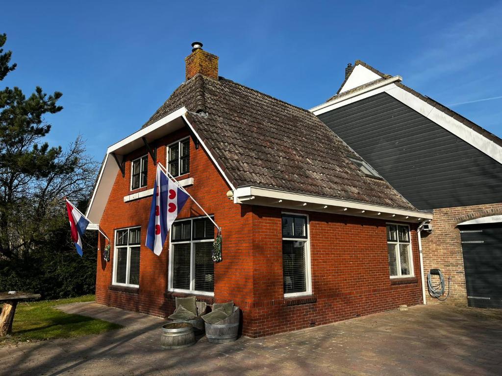 a red brick house with flags in front of it at Veendijkhoeve in Oosterwolde