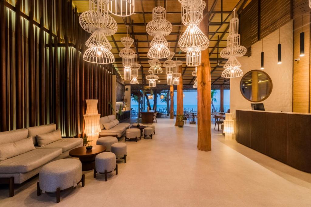 a lobby with couches and chairs and chandeliers at The Flow Samui Beach Resort in Koh Samui 