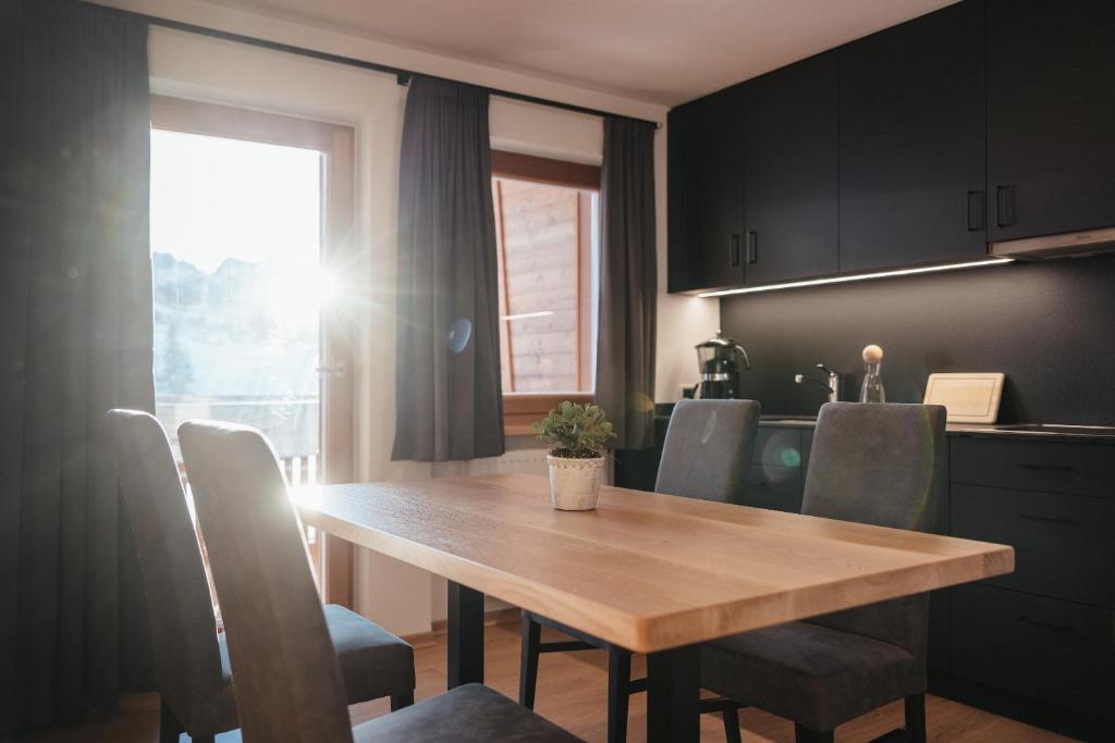 a kitchen with a wooden table and chairs and a window at Ciasa Willy App Conturines in La Villa