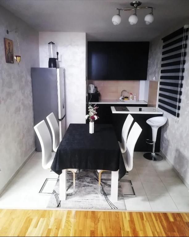 a kitchen with a black table and white chairs at Nenadovic Apartman in Obrenovac