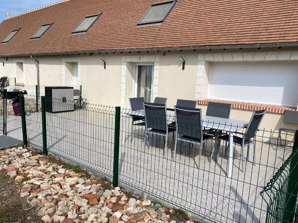 una valla con mesa y sillas frente a una casa en La maison des biquettes, en Romorantin-Lanthenay