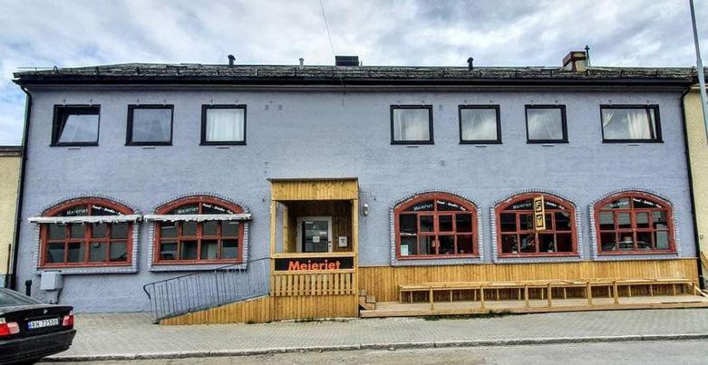 un edificio blanco con ventanas rojas en una calle en Meieriet, en Vardø