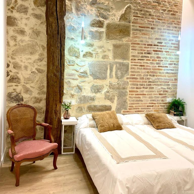 1 dormitorio con cama, silla y pared de ladrillo en Lauramer Casco Viejo, en Bilbao