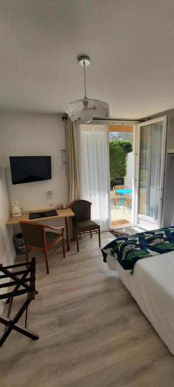 um quarto com uma cama, uma secretária e uma televisão em Auberge du Gros Tilleul em Argoules
