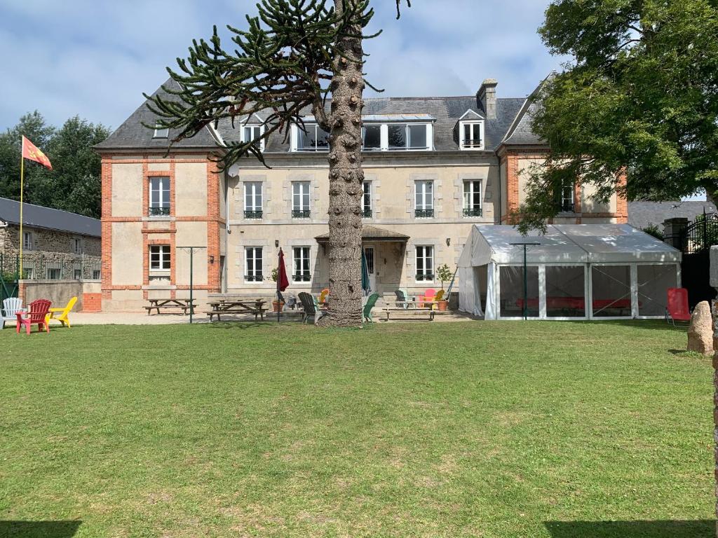 un gran edificio con un árbol delante en Gîtes grands groupes - Château des Forges Gouville, en Gouville-sur-Mer