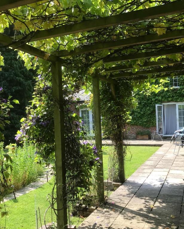 a wooden pergola in a garden with flowers at The Old Coach House at Stewton in Louth