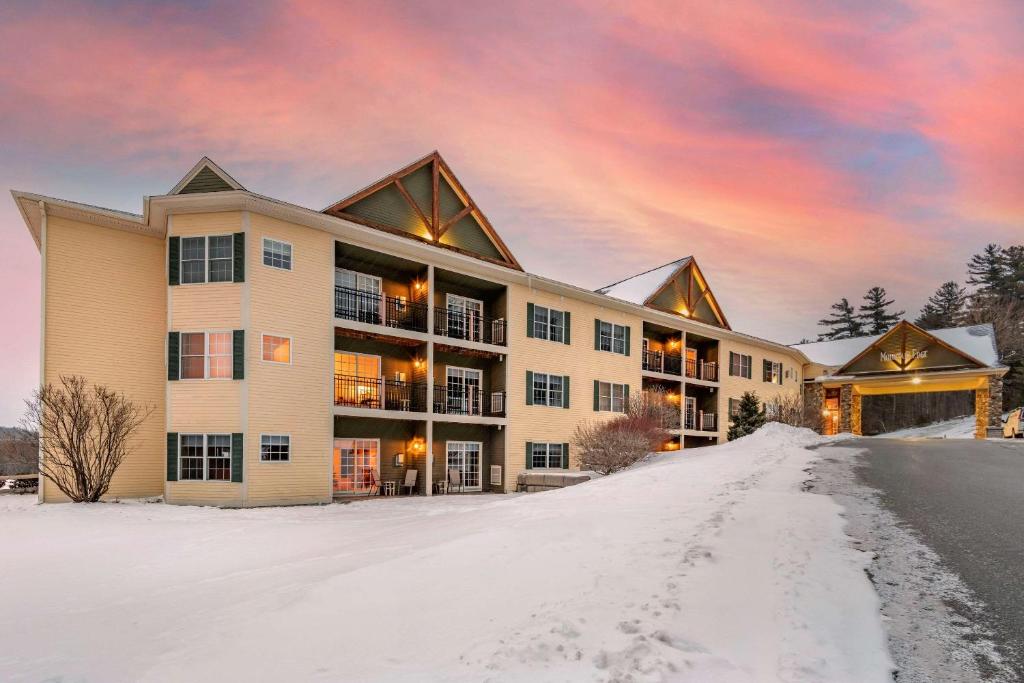 a building with snow in front of it at Mountain Edge Suites at Sunapee, Ascend Hotel Collection in Newbury