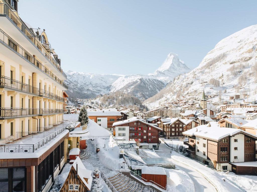 a town covered in snow with mountains in the background at BEAUSiTE Zermatt in Zermatt